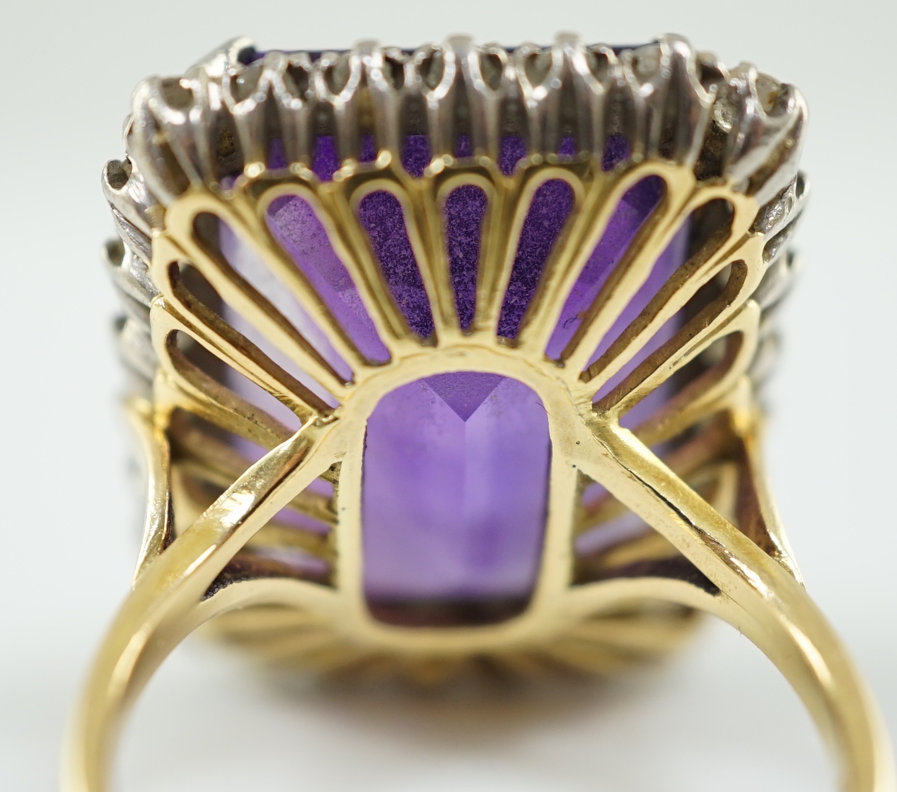 A large modern 18ct gold and emerald cut amethyst set dress ring, with diamond set border